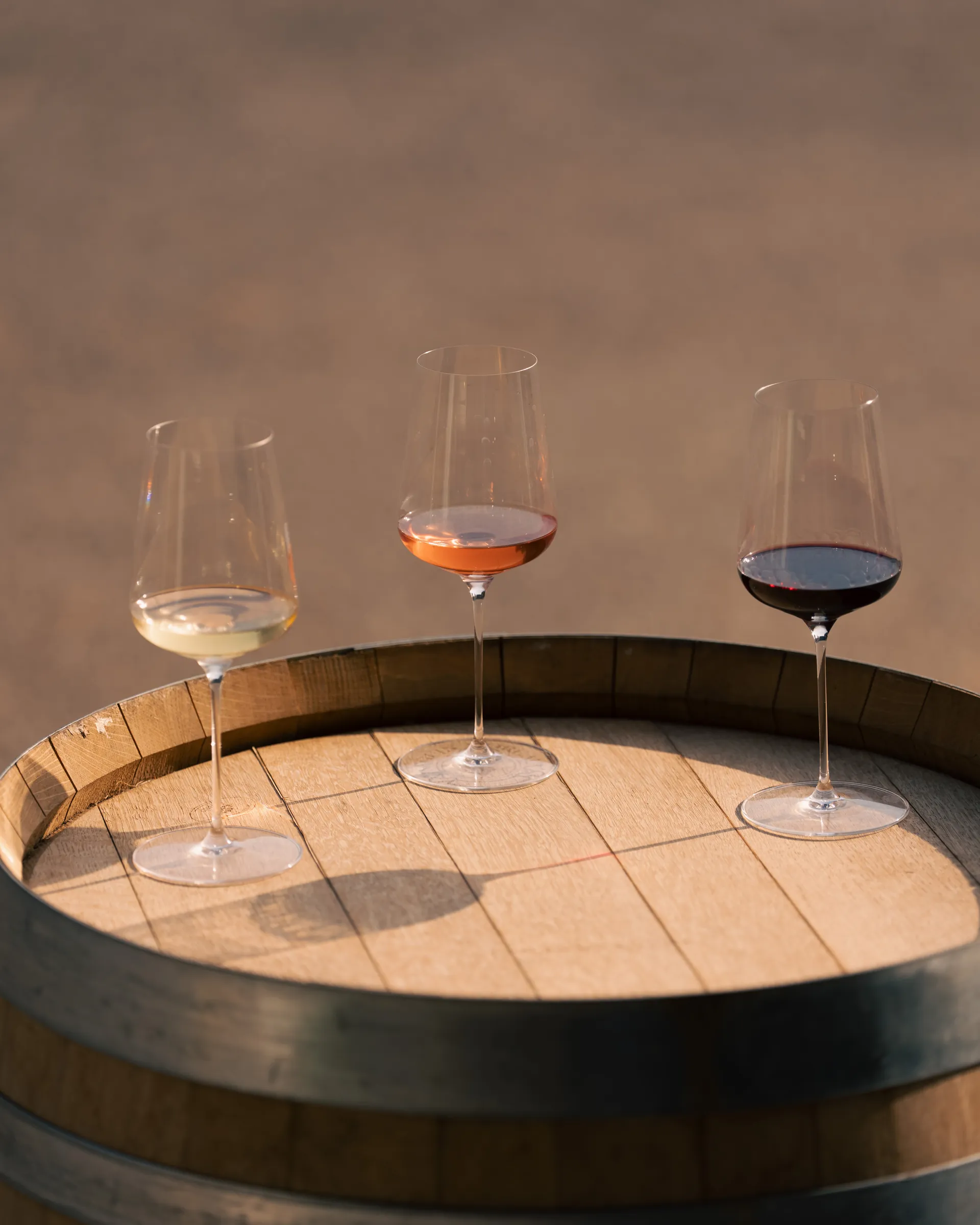 Trois verres de vin, blanc, rosé et rouge, sur un fût de chêne au Mas Rouvier