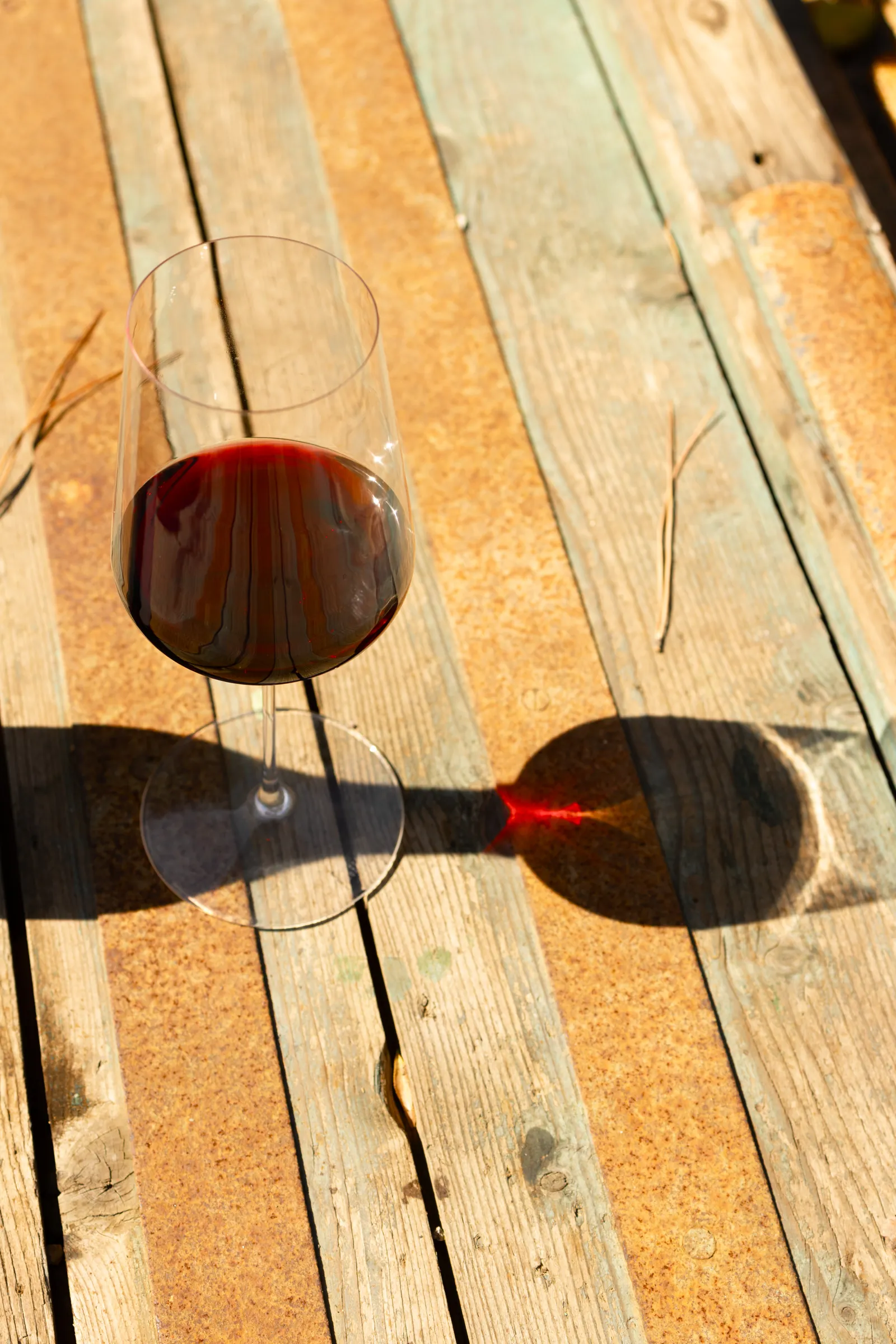 Verre de vin rouge sur une table en bois, lumière de fin de journée au Mas Rouvier